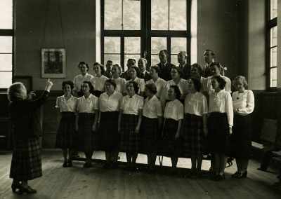 Zoom in Miss Ethel Bassin rehearsing the Choir