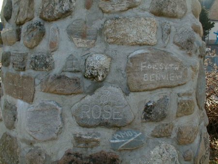 A close-up showing some of the villagers' names inscribed on the stones of the cairn.
