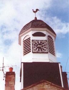 Octagonal wooden cupola with a pedimented clock face on its south front