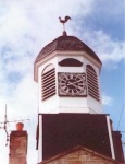 Octagonal wooden cupola with a pedimented clock face on its south front
